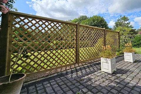 Diamond trellis panels with paved patio and raised planters in garden setting